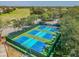 Aerial view of vibrant blue and green pickleball courts, offering a fun and active lifestyle at 18845 Fairway Green Dr, Hudson, FL 34667