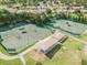 Aerial view of tennis courts with shaded seating areas, perfect for enjoying a friendly match at 18845 Fairway Green Dr, Hudson, FL 34667