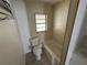 A bathroom with tiled floors and walls, a toilet, and a bathtub with a small window at 221 Highland St, Brooksville, FL 34601