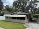 Charming single-story home with a covered carport and large windows under a shady tree at 221 Highland St, Brooksville, FL 34601