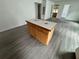 The open-concept kitchen features a wooden island with a tile countertop, gray wood-look floors, and plenty of cabinet space at 221 Highland St, Brooksville, FL 34601
