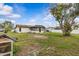 Backyard view showing house exterior with sunroom, mature trees, and grass lawn at 2450 Ambassador Ave, Spring Hill, FL 34609
