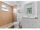 Bathroom featuring a tiled shower, toilet, sink and vanity with a white wicker mirror at 2450 Ambassador Ave, Spring Hill, FL 34609