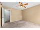 Bright bedroom with neutral walls and carpet, a ceiling fan, and door to the hall at 2450 Ambassador Ave, Spring Hill, FL 34609