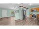 Open-concept living area with wood-look flooring, ceiling fan, and stainless refrigerator at 2450 Ambassador Ave, Spring Hill, FL 34609
