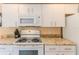 Kitchen featuring granite counters, microwave, and an electric range at 2481 Whispering Pines Ct, Spring Hill, FL 34606