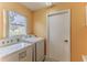 Well-lit laundry room featuring a modern washer and dryer set next to a window and a door at 2481 Whispering Pines Ct, Spring Hill, FL 34606