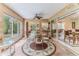 Bright sunroom features tile flooring, a glass table, ceiling fan, and backyard access at 2481 Whispering Pines Ct, Spring Hill, FL 34606