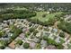 A high aerial view captures a quiet neighborhood next to a golf course with many trees and well-maintained yards at 2486 Deer Trail Ln, Spring Hill, FL 34606