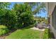 Relaxing backyard patio features an outdoor table set and lush green lawn and landscaping at 2486 Deer Trail Ln, Spring Hill, FL 34606