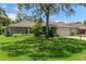 Charming single-story home featuring lush green lawn, mature trees, and a two-car garage at 2486 Deer Trail Ln, Spring Hill, FL 34606