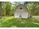 Spacious two-car garage with a barn-like shape with green grass and beautiful surrounding trees at 27091 Country Oak Dr, Brooksville, FL 34602