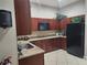 Clubhouse kitchen area with tile floors, granite countertops, dark wood cabinets, and black appliances at 2930 Plantain Dr, Holiday, FL 34691
