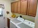 Well-lit laundry room with upper cabinets, side-by-side appliances, and exterior access at 2930 Plantain Dr, Holiday, FL 34691