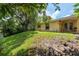 Large grassy backyard featuring mature trees, a lawn, and a view of the home's exterior at 3140 Bahia Ave, Holiday, FL 34690