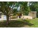 Exterior view of a cozy yellow house with lush landscaping and mature trees at 3140 Bahia Ave, Holiday, FL 34690