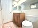 Well-lit bathroom with a wood vanity, large mirror, and a white toilet at 3151 Wellington Dr, Holiday, FL 34691