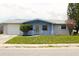 Charming single-story home featuring a blue front facade, well-maintained lawn, and attached garage at 3151 Wellington Dr, Holiday, FL 34691