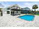 Backyard view of pool and home with black railinged deck, and a paved patio area at 4104 Pine Dale Ct, Hernando Beach, FL 34607