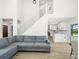 Open-concept living room featuring a gray sofa, staircase, and modern kitchen at 4104 Pine Dale Ct, Hernando Beach, FL 34607