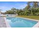 Relaxing backyard with sparkling blue pool and inviting blue Adirondack chairs under sunny sky at 4479 Bluewater Ave, Spring Hill, FL 34606
