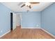 Empty blue bedroom with hardwood floors, ceiling fan, and white door to the closet at 507 Jewel St, Brooksville, FL 34601