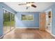 Blue bedroom featuring sliding glass doors, hardwood floors, ceiling fan, and wood door to the bathroom at 507 Jewel St, Brooksville, FL 34601