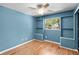 Blue bedroom with hardwood floors, ceiling fan, window, and built-in shelves and storage at 507 Jewel St, Brooksville, FL 34601