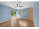 Light blue bedroom featuring sliding glass doors, hardwood floors, ceiling fan, and wood door at 507 Jewel St, Brooksville, FL 34601