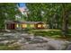 Single-story home with a red door, surrounded by mature trees and a spacious yard at 507 Jewel St, Brooksville, FL 34601