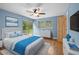 Staged blue main bedroom featuring a sliding glass door, hardwood floors, ceiling fan, and wood door at 507 Jewel St, Brooksville, FL 34601