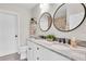 Bathroom featuring dual sinks, marble countertops, and stylish round mirrors at 5440 Manatee Point Drive, New Port Richey, FL 34652