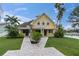 Charming yellow home with a paver walkway, lush landscaping, and a pergola at 5440 Manatee Point Drive, New Port Richey, FL 34652