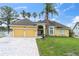 Charming yellow home with a two-car garage, brick driveway, manicured lawn, and mature palm trees at 5440 Manatee Point Drive, New Port Richey, FL 34652
