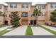 Townhouse exterior with two-car driveways, garages, balcony, neutral paint, dark accents, and manicured landscaping at 5520 White Marlin Ct, New Port Richey, FL 34652