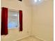 Cozy bedroom with neutral carpet, a small window with red curtains, and neutral walls at 6462 92Nd N Pl # 806, Pinellas Park, FL 33782