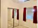 Bright bedroom featuring a mirrored closet, neutral carpet, and a small window with red curtains at 6462 92Nd N Pl # 806, Pinellas Park, FL 33782