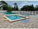 Community pool and hot tub surrounded by lush landscaping and white lounge chairs on a sunny day at 6462 92Nd N Pl # 806, Pinellas Park, FL 33782