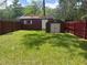 Spacious backyard with grass, a shed, and a red wooden fence, great for outdoor activities at 717 Whiteway Dr, Brooksville, FL 34601