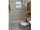 Bathroom features a tiled shower-over-tub, tiled walls and floors, and natural-wood shelving unit at 717 Whiteway Dr, Brooksville, FL 34601
