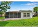 View of the rear exterior featuring a screened patio and white stucco walls at 7316 Tangelo Ave, Port Richey, FL 34668