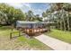Picturesque home featuring a wooden deck, complemented by lush greenery and a spacious yard at 7424 Grand Blvd, New Port Richey, FL 34652