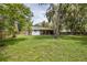 Landscaped backyard featuring mature trees and green space with a covered patio at 7424 Grand Blvd, New Port Richey, FL 34652