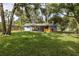 Spacious backyard with lush green grass, mature trees, and a covered patio at 7424 Grand Blvd, New Port Richey, FL 34652