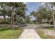 View of the street and sidewalk leading to a house surrounded by lush trees at 7424 Grand Blvd, New Port Richey, FL 34652