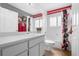 Bathroom with a combination shower and tub, white vanity, and red floral accents at 7923 Woburn St, New Port Richey, FL 34653