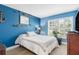 Cozy bedroom featuring blue walls, plantation shutters, and a comfortable bed with decorative pillows at 7923 Woburn St, New Port Richey, FL 34653