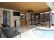 Inviting covered pool patio with tiled floor, ceiling fan, bar seating, TV, and direct access to the pool at 9003 Lido Ln, Port Richey, FL 34668