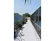 Paver walkway alongside the home leads to the screened in pool, featuring tropical plants and privacy fence at 9003 Lido Ln, Port Richey, FL 34668