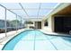 The in-ground swimming pool sparkles in the sun inside the screened-in lanai at 9003 Lido Ln, Port Richey, FL 34668